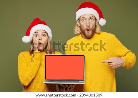 Merry sad young couple two IT friends man woman wear sweater Santa hat posing work use blank screen area laptop pc computer isolated on plain green background Happy New Year Christmas holiday concept