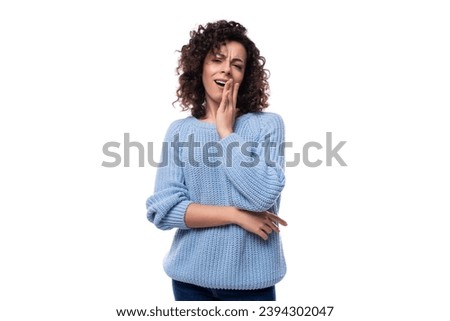 portrait of a charming young caucasian woman with curly dark hair dressed in a casual warm blue blouse on a white background with copy space