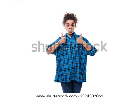 young beautiful european woman with curly hair is dressed in a blue plaid shirt with a surprised grimace on a white background
