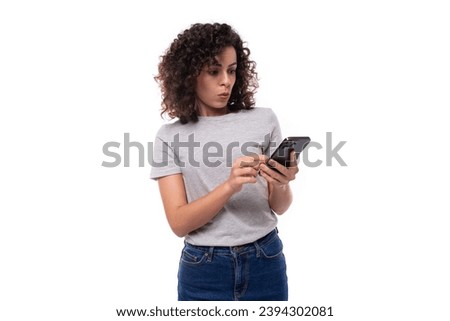 young indignant slender 30 year old caucasian woman with curly hair in a gray t-shirt on a white background with copy space