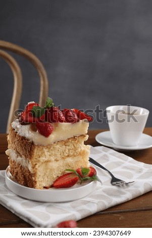 Piece of tasty cake with fresh strawberries, mint and cup of tea on wooden table Royalty-Free Stock Photo #2394307649