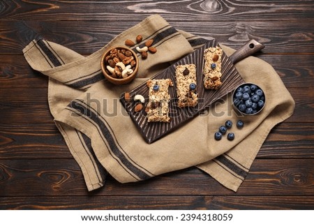Tasty granola bars and ingredients on wooden table, flat lay Royalty-Free Stock Photo #2394318059