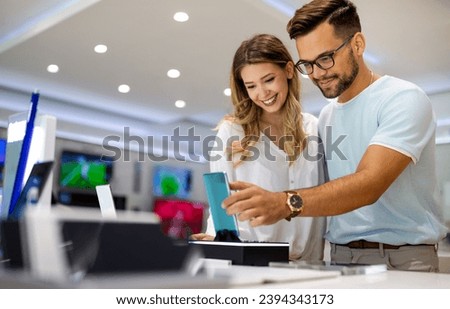 Tech shopping device gadget concept. Happy young people buying a new smartphone in mobile shop. Royalty-Free Stock Photo #2394343173