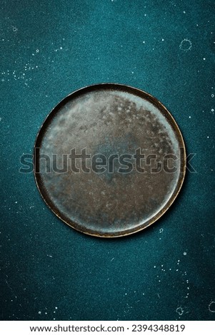 A dark stone plate on a blue stone table. Free copy space. Top view.