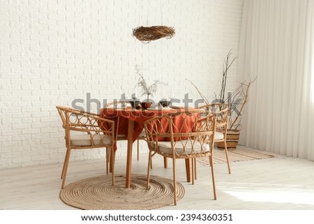 Autumn table setting with burning candles and dry leaves in light room
