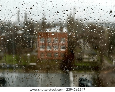 Rainy day in the industrial city. View through wet window with raindrops moment seeing industrial area during rain storm. Background.
