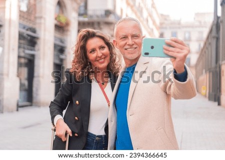 Affectionate husband and wife taking a selfie with a smartphone in their holidays. Two people, man and female in a tour taking a photo with a mobile phone smiling and laughing at camera