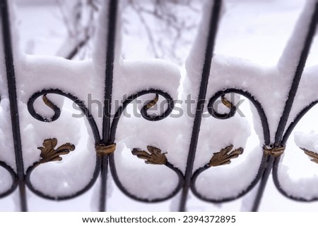 Elements of a wrought iron fence covered with snow. Snowy winter background. 