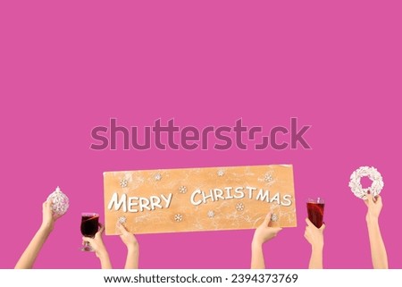 Female hands with glasses of warm mulled wine and Christmas decor on pink background