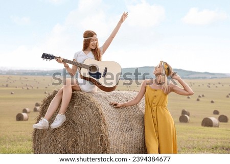 Beautiful happy hippie women with guitar in field