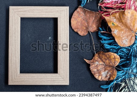 Autumn concept. Top view photo of wooden photo frame of yellow maple leaves and plaid on isolated black background with empty space