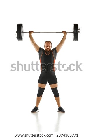 Bearded strong man, athlete training, lifting heavy weights, barbell against white background. Muscular strong body. Concept of sport, strength, gym, healthy lifestyle, power, endurance, weightlifting