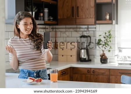 Young woman influencer vlogging over her smartphone in her modern home kitchen