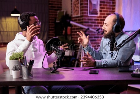Skillful host engaging in entertaining discussion with celebrity during live stream in professional studio. Presenter using high quality cameras, microphones and neon lights to enhance online show