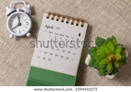 Desk calendar for April 2024 and a clock on the table Royalty-Free Stock Photo #2394410273