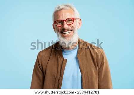Portrait handsome smiling 50 years old mature man with stylish gray hair wearing red hipster glasses looking at camera isolated on blue background. Vision concept 