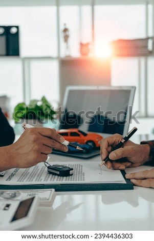 A car dealer with a customer, the new owner, signs a lease-purchase document. car sales contract The employee explains the installment payment terms. vertical picture