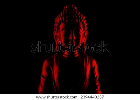 Buddha Purnima and Vesak day concept, Red Buddha statue with low key light against deep black background close up. Meditation