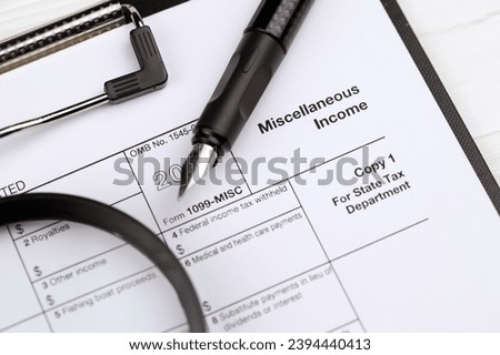 IRS Form 1099-misc Miscellaneous income blank on A4 tablet lies on office table with pen and magnifying glass close up Royalty-Free Stock Photo #2394440413