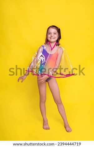 smiling child girl dance in raincoat on yellow background. ready for tropical rainy showers