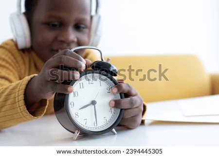 Selective focus of African boy using clock to set time for study, break time, concept of deadline and clock time control