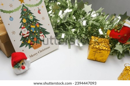 Christmas elements with green paper grass background. Holiday greeting card with a picture of a Christmas tree in front of paper grass along with other Christmas elements