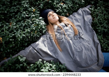Portrait of a young beautiful blond woman, broadly smiles in warm clothing lying on ground at winter. Lifestyle concept.