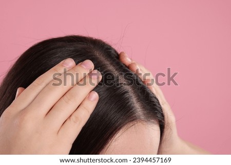 Woman examining her hair and scalp on pink background, closeup. Space for text Royalty-Free Stock Photo #2394457169