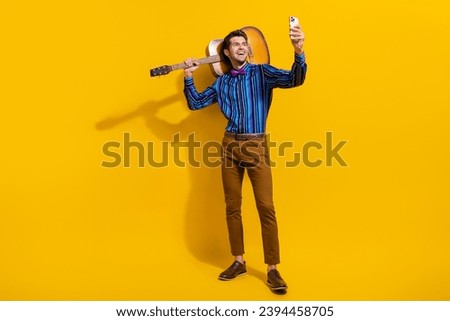 Full size photo of nice guy dressed shirt hold acoustic guitar on shoulder make selfie on smartphone isolated on yellow color background