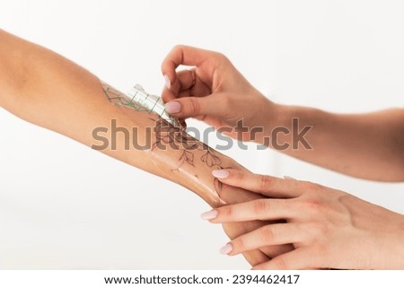 Close-up hands of master Tattoo artist in black gloves sticking paper with pattern on client's hand