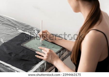 a young female artist designing new tattoo sketch on a tablet