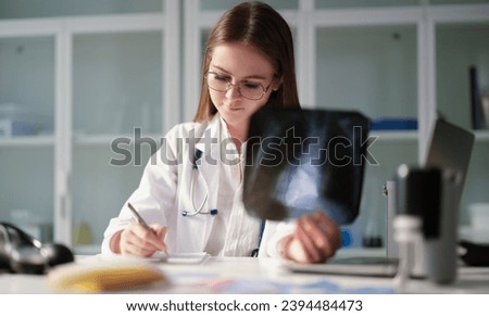 Therapist doctor holding xray of lungs in hands and writing in medical documents in clinic. Diagnosis and treatment of pneumonia and lung cancer concept
