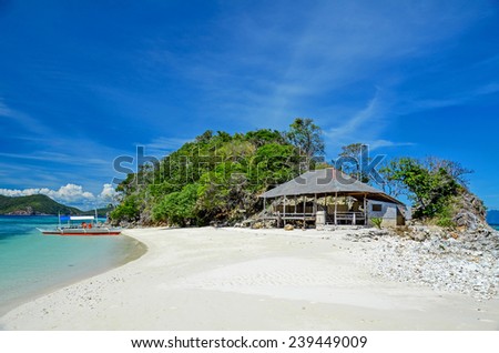 Sandy beach with bungalows and a boat near the island of Busuanga. Philippines