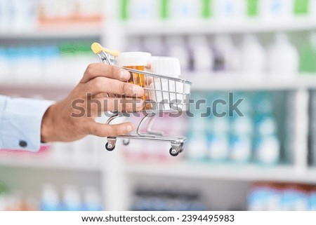 Young hispanic man pharmacist holding market kart with pills at street