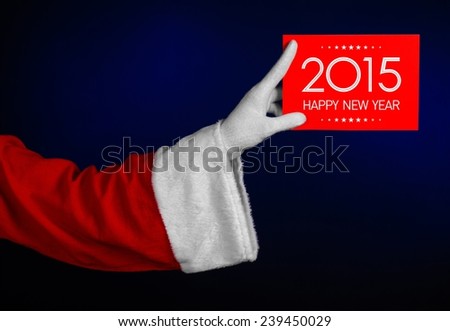 Christmas theme: Santa's hand holding a red card with New Year Greetings 2015 on a dark blue background isolated