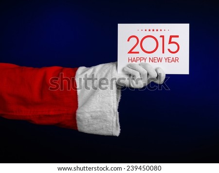 Christmas and New Year theme: Santa's hand holding a white card with a New Year's greetings in 2015 on a dark blue background isolated
