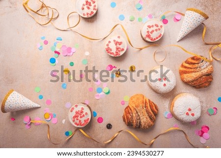 Berliner, cinnamon rolls and cupcakes for carnival and party. German Krapfen or donuts with streamers and confetti. Colorful carnival or birthday image