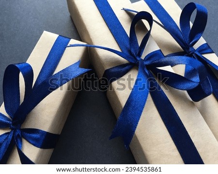 Three gift boxes with a blue satin ribbon bows on a dark background. Close-up