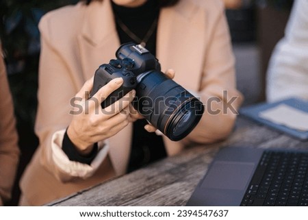 Close-up of photographer holding mirrorless camera and checking pictures.  Royalty-Free Stock Photo #2394547637