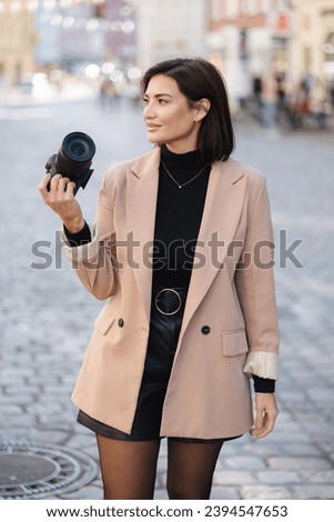 Portrait of elegant female photographer with dslr camera in the city. Woman walking in city and make photos