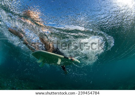 muscular surfer with long white hair riding on big waves on the Indian Ocean island of Mauritius, picture was taken under water