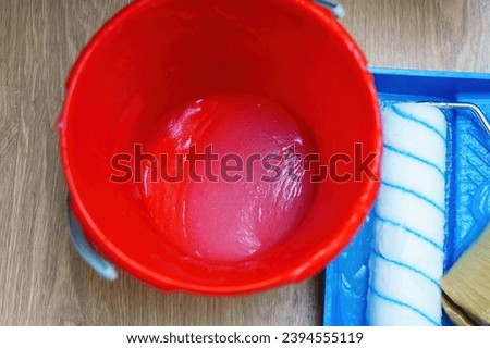 Translucent wallpaper glue in a red bucket Royalty-Free Stock Photo #2394555119
