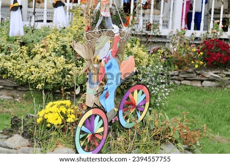 A scarecrow riding on a colorful bike decoration.