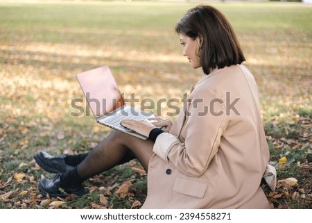 Beautiful woman working on laptop in the park. Attractive freelancer on outdoors.