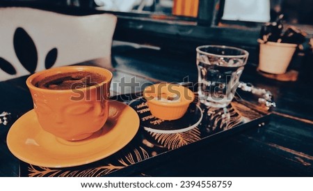 a cup of Turkish coffee served on a tray on a green wooden table, a glass of water and Turkish delight in a small ceramic plate in coffee shop. Vintage effect picture style pictures 