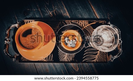 a cup of Turkish coffee served on a tray on a green wooden table, a glass of water and Turkish delight in a small ceramic plate in coffee shop.  Vintage effect picture style pictures
