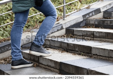 woman climbing the stone steps of the stairs. stone staircase with autumn leaves. High quality photo