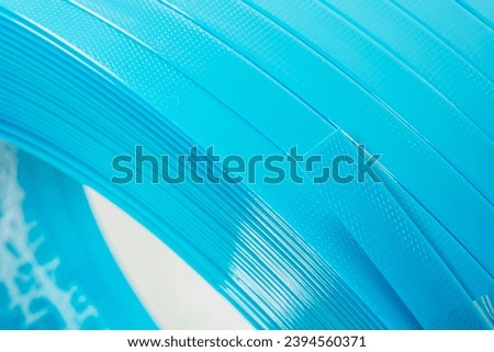 blue polyester tape on a white background. high-strength temoplastic tape in a roll on a light background. tape packaging material in roll Royalty-Free Stock Photo #2394560371