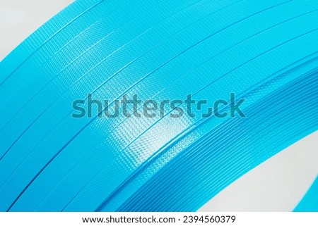 blue polyester tape on a white background. high-strength temoplastic tape in a roll on a light background. tape packaging material in roll Royalty-Free Stock Photo #2394560379