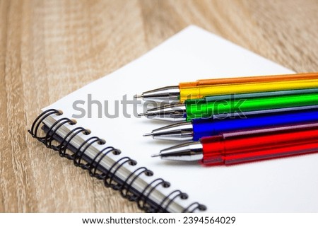 Ballpoint pens. Choice of handles. Colored pens. Ink pens for writing. Pens lie on the notepad page. Office stationery concept. Royalty-Free Stock Photo #2394564029